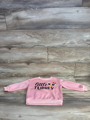 Pink toddler sweatshirt with 'little TURKEY' text and turkey graphic, laid on wood floor