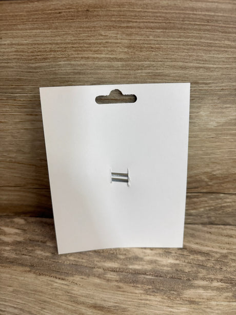Front view of Layered Crown Glitter Hair Bow packaging showing empty white display card with two silver prongs on wood background