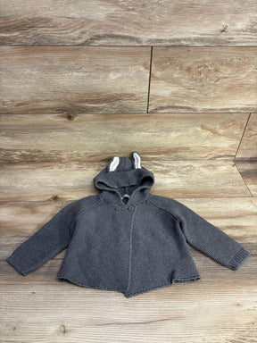 Gray knit baby sweater with hood and ear details, laid flat on wood background