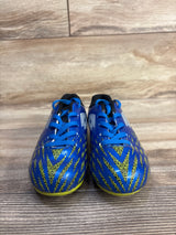 Front view of Lotto Forza Jr soccer cleats showing blue upper, yellow geometric pattern, and blue laces on wood floor