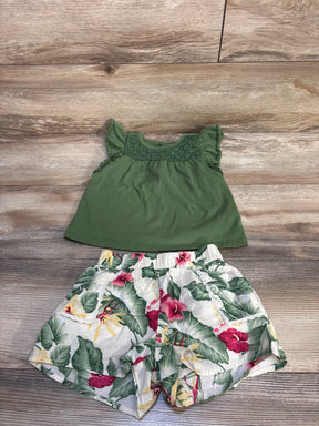 Green ruffle sleeve toddler top with floral print shorts on wood background