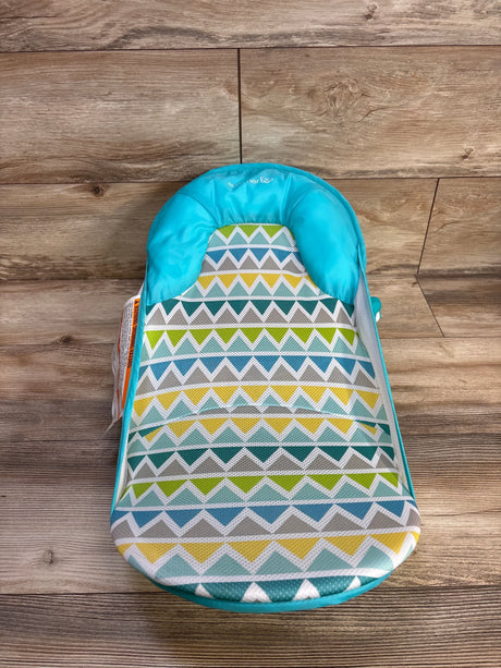 Top-down view of Summer Deluxe Baby Bather in teal and green showcasing padded headrest and geometric chevron mesh fabric with wood floor background