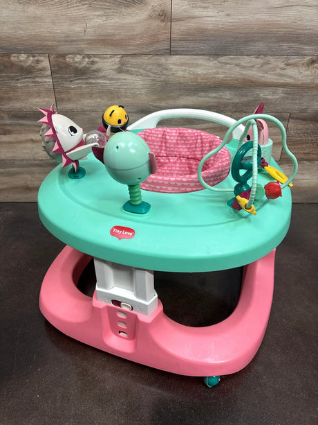 Front view of Tiny Love 4-in-1 Here I Grow Activity Center in Tiny Princess with attached toys and pink seat against wood backdrop