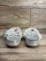 Pair of small silver glitter baby moccasin slippers with faux fur lining and satin bows on wooden floor
