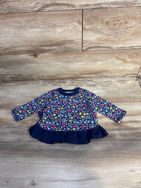 Navy blue baby dress with colorful floral print and ruffle hem on wood background