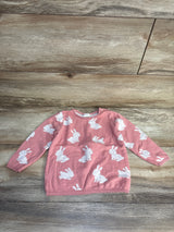 Pink baby sweater with white bunny print, long sleeves, laid on wood floor