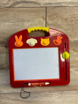 Front view of B. Toys LapTrec magnetic board with animal stamp knobs, stylus, and yellow erase slider on wood floor