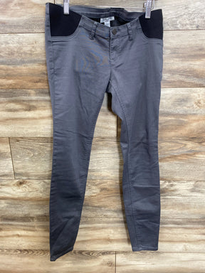 Gray maternity pants with black belly panel, hanging on hanger against wood background