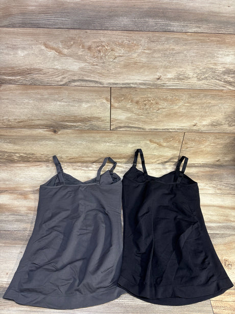 Flat lay of two nursing tank tops (grey and black) with adjustable shoulder straps and inner shelf on wood floor background