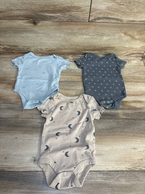 Three baby onesies with moon, star, and paper airplane prints on wood floor, ideal for newborns and infants.