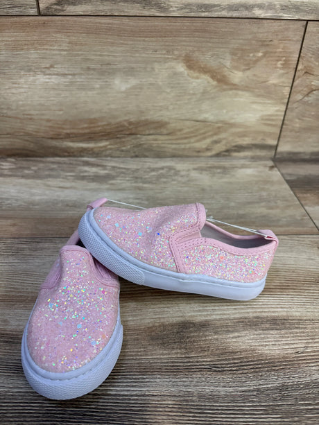 Angled view of Cat and Jack Yana toddler slip-on sneaker size 7C showing pink iridescent glitter upper and white rubber sole on wood surface