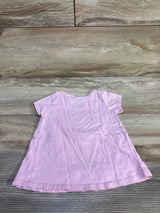 Back view of pink baby short-sleeve A-line shirt laid flat on wood background