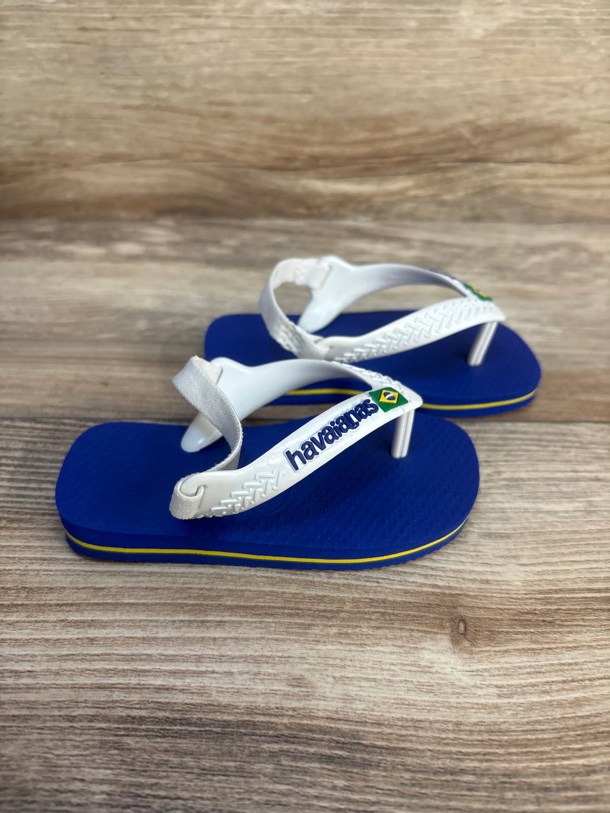 Blue and white Havaianas toddler sandals with elastic heel strap on wood background