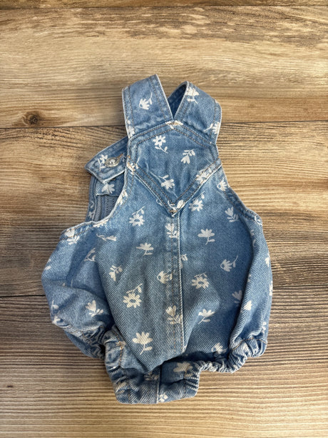 Baby denim romper with white floral print on wood background, gently used children’s clothing
