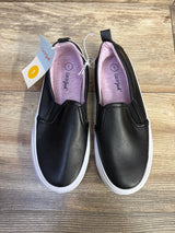 Top-down view of Cat and Jack Hailey slip-on toddler sneakers in black showing white rubber sole, pink inner lining and size 1 tag on wood floor background