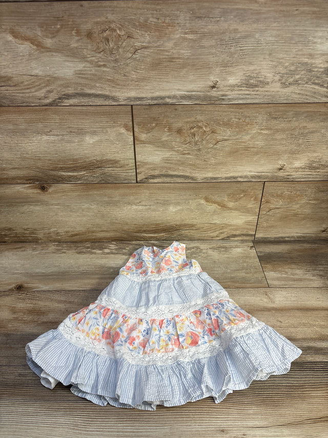 Flat lay of girls Tommy Bahama tiered sleeveless dress, blue-and-white seersucker and floral tiers with lace trim on wood