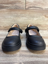 Black girls' Mary Jane dress shoes with strap, displayed on wooden floor