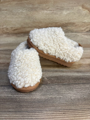 Pair of cozy cream toddler sherpa slippers with tan soles on wood background