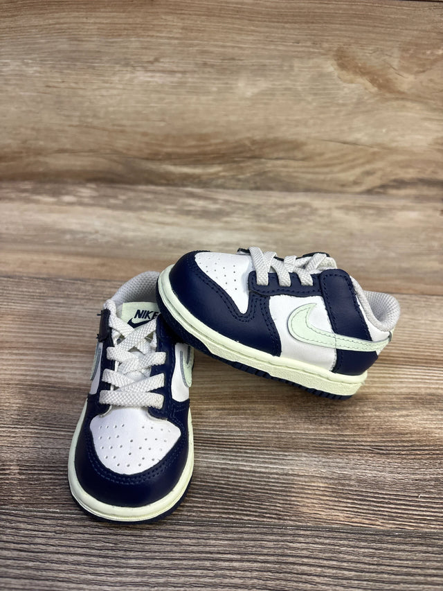 Front and side view of toddler Nike Dunk Low sneakers in midnight navy and white with pale green Swoosh, size 4C on wood background