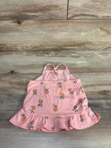 Flat lay of pink OshKosh 24-month tank top with pineapple print, ruffle hem, and crossed straps on light wood background