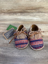 Patterned baby moccasins with fringe and laces on wooden background, baby shoes resale