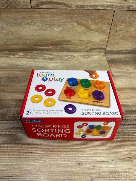 Angled view of Lakeshore Learn and Play Color Rings Sorting Board with colorful rings and wooden pegs on wood floor