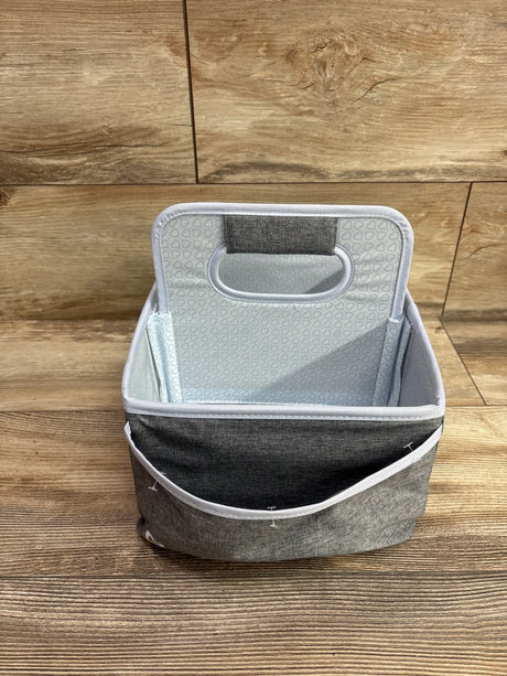 Front view of the grey Munchkin portable diaper caddy organizer showing its open compartment and handle on wood flooring
