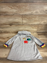 Flat lay of grey sweater dress showing rainbow cuffs and front patches including Save the World patch and red apple on wood