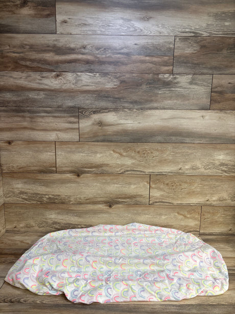 Flat lay of Cloud Island fitted crib sheet showcasing pastel rainbow arches on white with wood plank backdrop