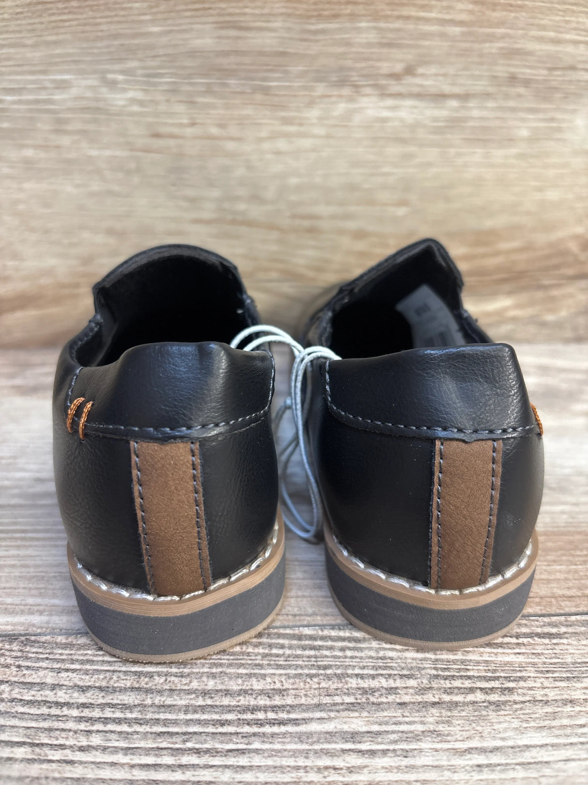 Back view of black and brown toddler dress shoes on wooden surface