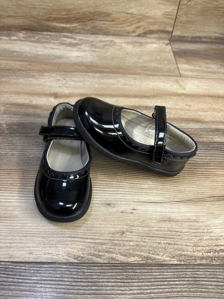 Front and side view of See Kai Run Jane II Mary Jane shoes, glossy black patent with scalloped trim and hook-and-loop strap on wood floor background