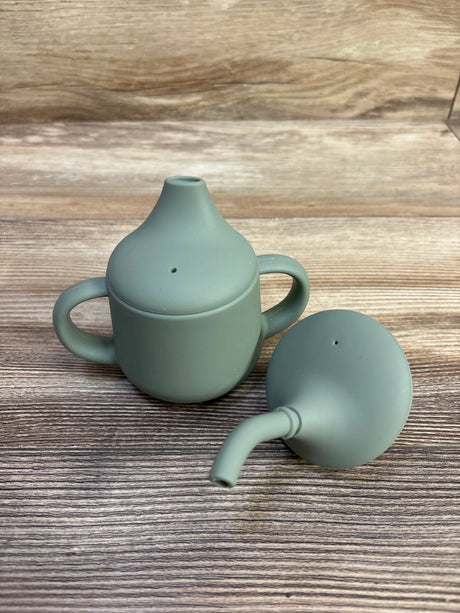 Front view of Moonkie 4 oz first-stage sippy cup set showing green silicone cup with two handles and extra spout on wood