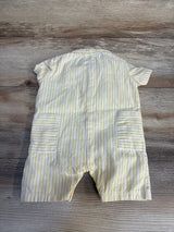 Yellow and white striped baby romper with short sleeves and back pockets on wood background