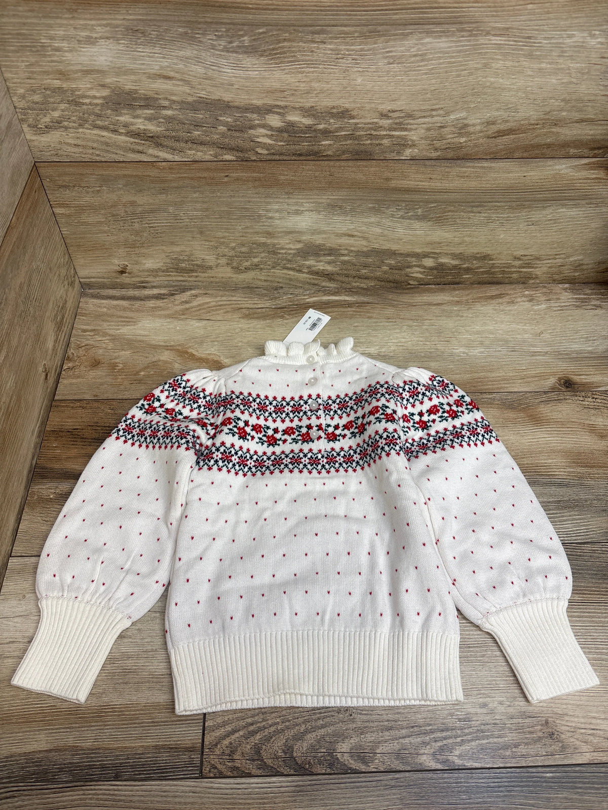 Front view of Janie and Jack white floral Fair Isle ruffle neck sweater in size 3T with long sleeves on a wood floor