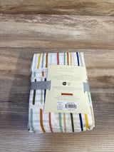 Folded Cloud Island fitted crib sheet showing multicolored dash stripes and product label on wood surface