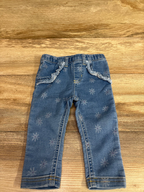 Front view of Cat & Jack blue floral jeggings in size 12 months showcasing an elastic waistband and stitched pockets on a wood-grain background