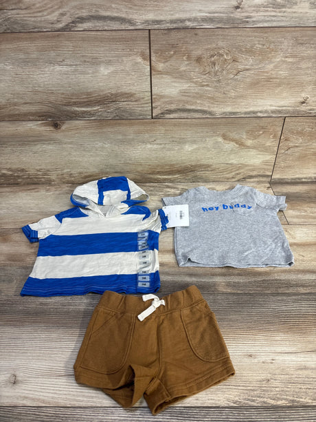 Flat lay of 3-piece baby set size 3M showing blue-and-white hooded shirt, grey hey buddy tee and brown shorts on wood background