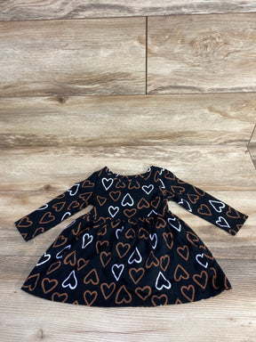 Long-sleeve black toddler dress with brown and white heart patterns on wooden floor