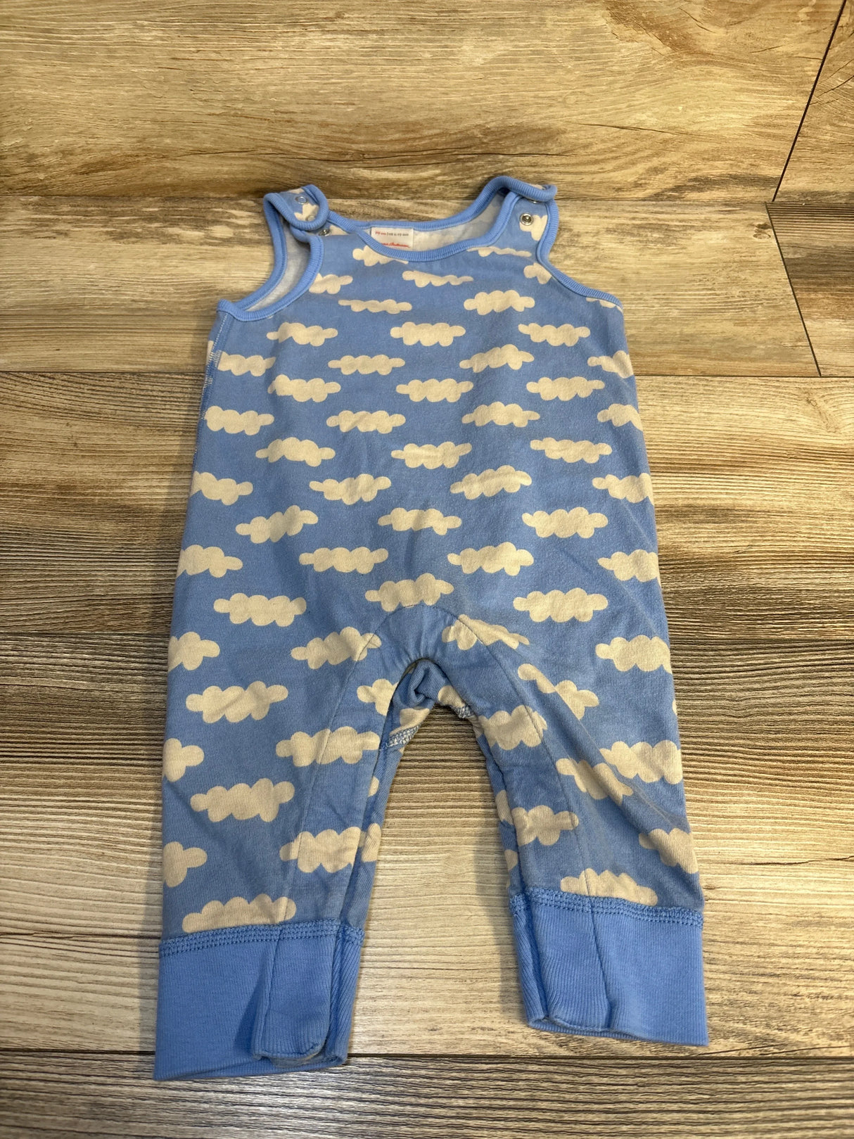 Blue baby romper with white cloud pattern on wooden floor
