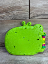 Rear of Cocomelon MacDonald Farm toy book showing green plastic back, battery compartment, embossed icons, and side rings