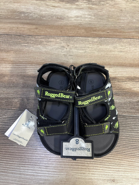 Top-down view of Rugged Bear black open-toe toddler sandals size 8C showing two Velcro straps with neon green RuggedBear logo and tag on wood floor