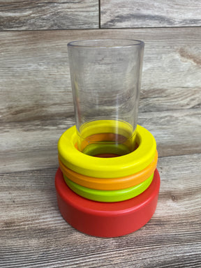 Clear plastic cup stacked inside colorful toy rings on wooden surface