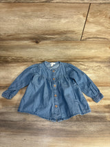 Baby denim long sleeve top with front buttons, laid on wood floor