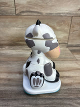 Side view of Stack-a-Roos Baby Cow stacking toy showcasing stacked cow-shaped rings, pink snout, and paw-print base on wood floor background