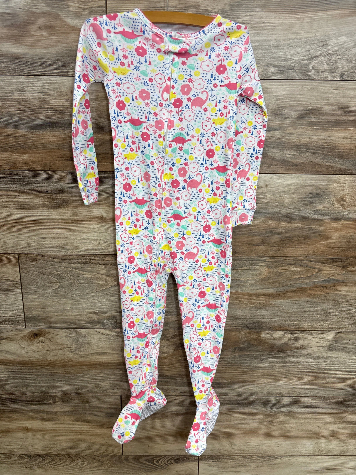 Colorful baby footed pajamas with dinosaur and floral print, long sleeve, zip front, on wood floor