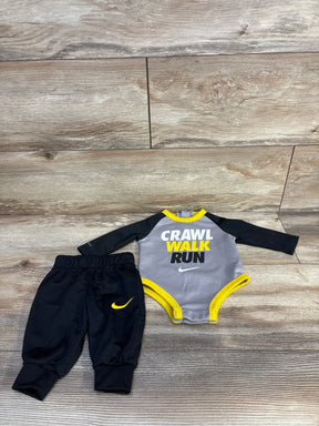 Nike baby outfit set with 'Crawl Walk Run' bodysuit and black pants on wood floor