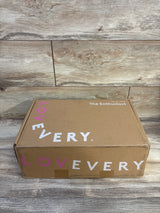 Top-front view of Lovevery play kit box showing LOVEVERY logo and 'The Enthusiast' label on wood background