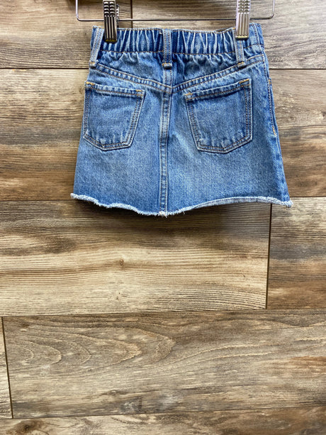 Front view of Old Navy blue denim skirt, size 2T, with elastic waistband, two pockets, and frayed hem on wood flooring