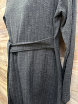 Close-up front of Ekouaer black ribbed maternity long-sleeve dress with waist tie on wooden background