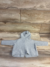 Front view of Baby Gap grey knit hooded cardigan in size 6 to 12 months showcasing hood and long sleeves on a wood floor